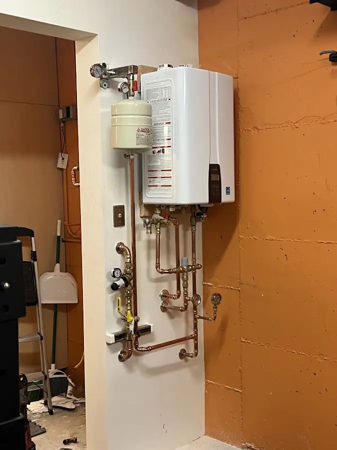 Plumbing technician inspecting water heater connections in Winooski